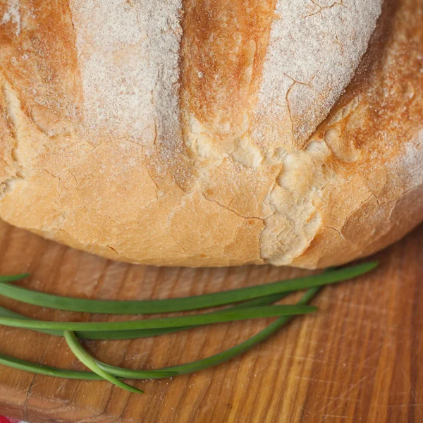 Crusty loaf at top view are on a wood table with green onion — Stock Photo, Image