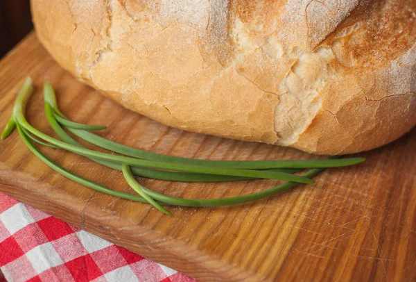 Ropogós kenyér: felülnézet van egy fából készült asztal zöld hagyma — Stock Fotó