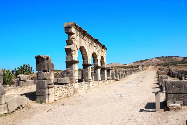 Arco y columnas en la calle Decumanus Maximus, Volubilis, Marruecos —  Fotos de Stock