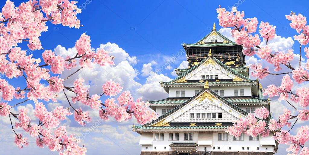Branch of the blossoming sakura with pink flowers and Osaka castle, Japan. On blue sky background