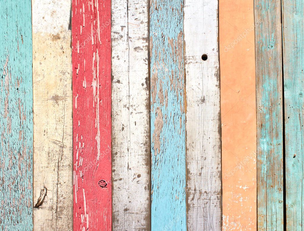 Texture of vintage wood boards with cracked paint of white, red, orange, yellow, cyan and blue color. Retro background with old wooden planks of different colors