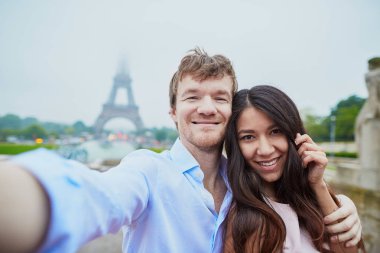 Romantik Çift Eiffel yakınındaki selfie alarak aşık Paris'te bulutlu ve sisli yağmurlu bir günde kule.