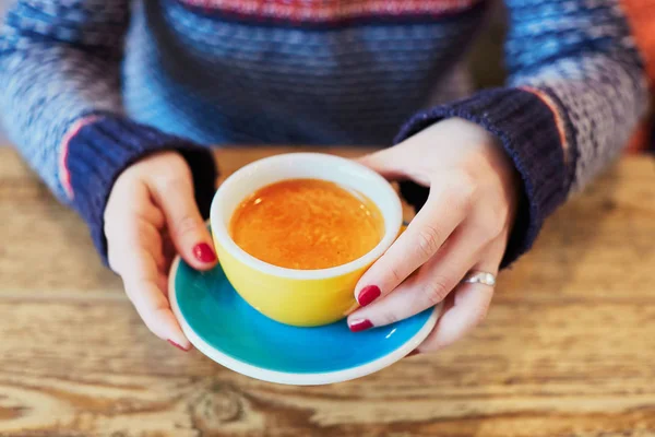 Belle mani di donna con manicure rossa e tazza di caffè caldo fresco sul tavolo di legno — Foto Stock