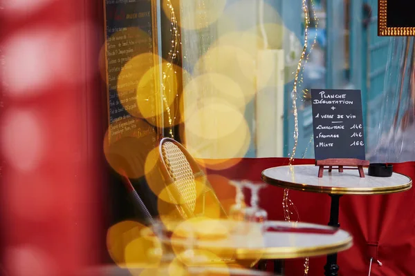 Acolhedor café ao ar livre parisiense com luzes amarelas e placa de menu na mesa — Fotografia de Stock