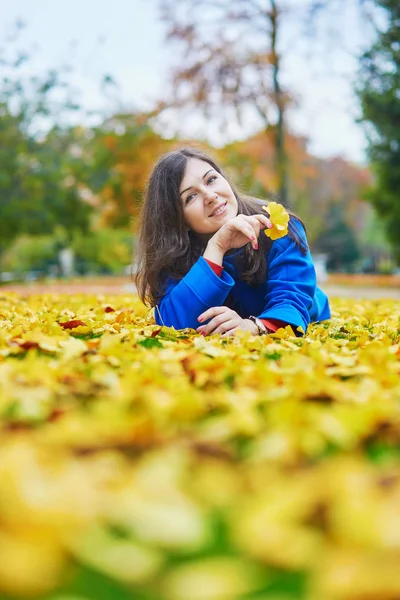 Mladá žena v den pádu na zem s barevné podzimní listí — Stock fotografie