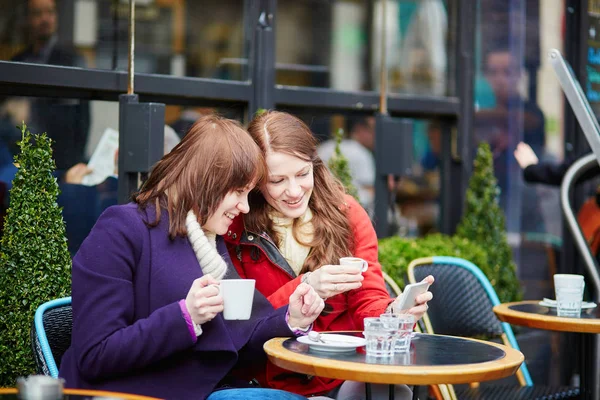 Δύο χαρούμενα κορίτσια που πίνουν καφέ σε ένα παριζιάνικο καφέ. — Φωτογραφία Αρχείου