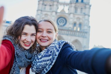 İki genç kız selfie alarak Notre-Dame de Paris yakınındaki