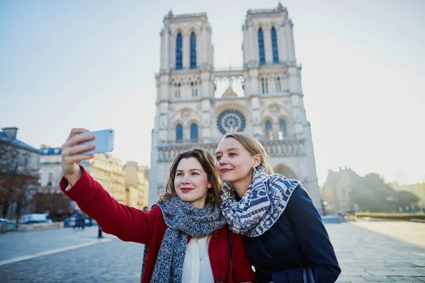İki genç kız selfie alarak Notre-Dame de Paris yakınındaki