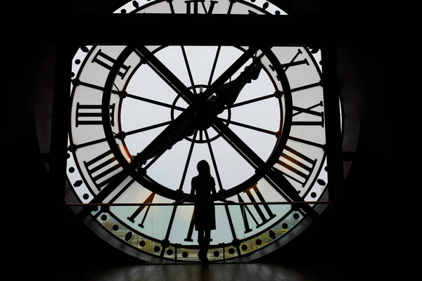 Woman silhouette standing in front of large clock — Stock Photo, Image