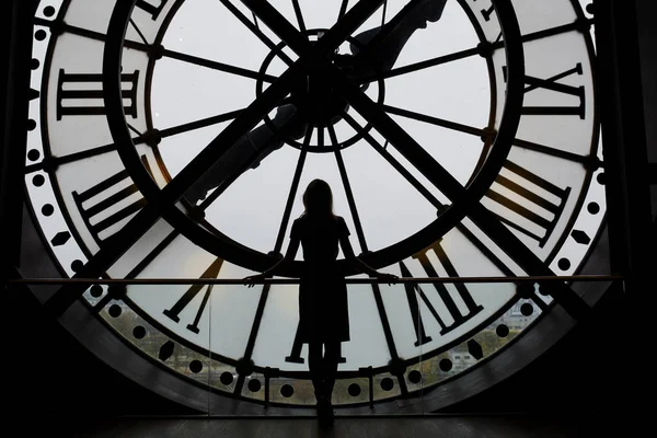 Woman silhouette standing in front of large clock — Stock Photo, Image