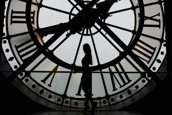Woman silhouette standing in front of large clock — Stock Photo, Image