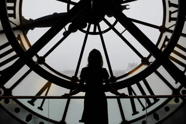 Woman silhouette standing in front of large clock — Stock Photo, Image