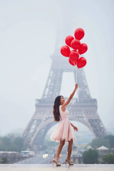 Mujer parisina con globos rojos frente a la torre Eiffel —  Fotos de Stock