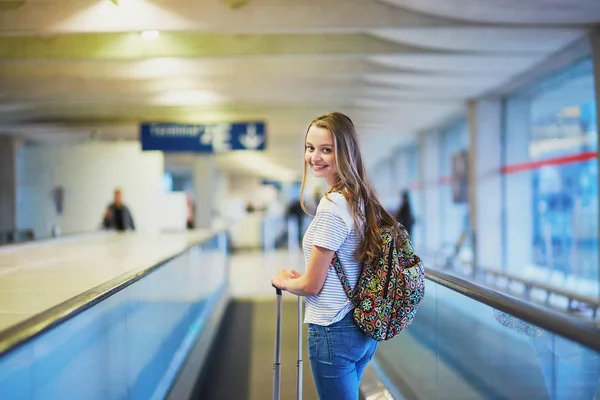 Девушка-туристка с рюкзаком и чемоданом в международном аэропорту — стоковое фото