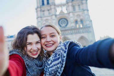 İki genç kız selfie alarak Notre-Dame de Paris yakınındaki