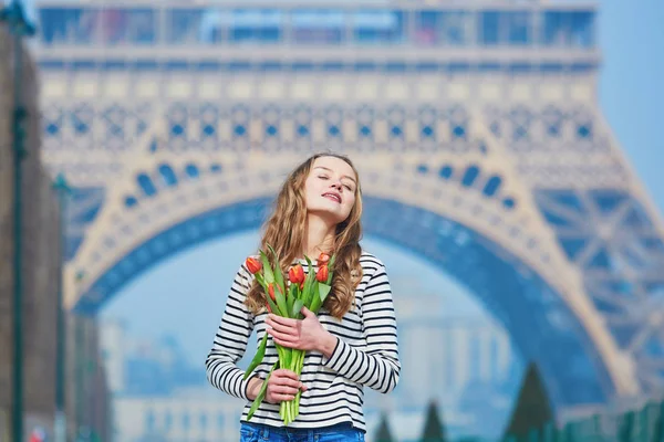 Menina com um monte de tulipas vermelhas perto da torre Eiffel — Fotografia de Stock