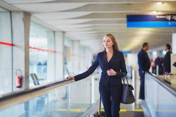在国际机场内的自动人行道上的女人 — 图库照片