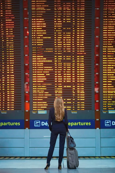 女人与手提行李在国际机场航站楼，看着信息板 — 图库照片
