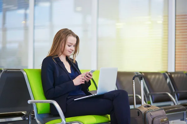 Женщина в международном аэропорту, проверяет телефон — стоковое фото