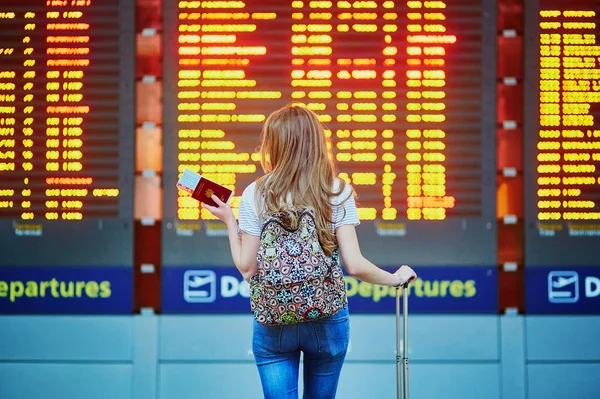 A hátizsák és a nemzetközi repülőtér, repülés információs tábla közelében poggyász folytasson turista lány — Stock Fotó