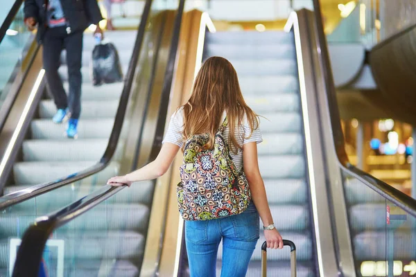 Menina turística com mochila e bagagem de mão no aeroporto internacional, na escada rolante — Fotografia de Stock