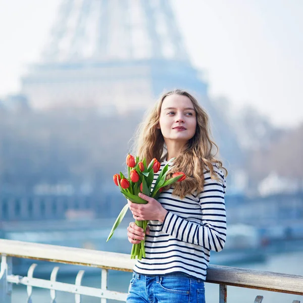 Девушка с кучей красных тюльпанов возле Эйфелевой башни — стоковое фото