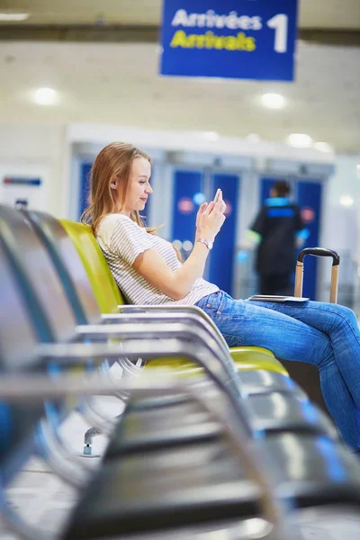 Jovem viajante no aeroporto internacional verificando seu telefone celular enquanto espera por seu voo — Fotografia de Stock