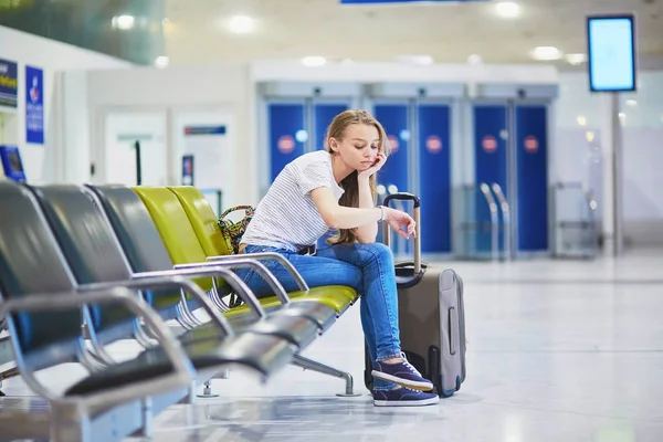 Tourist girl in international airport, waiting for her flight, looking upset — Stock Photo, Image