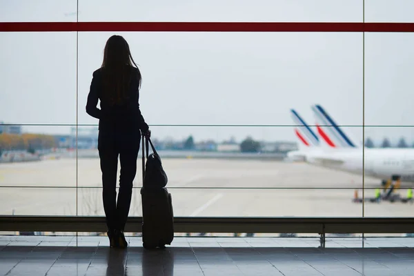 Γυναίκα με αποσκευές χειρός στην διεθνή αερολιμένα, κοιτάζοντας μέσα από το παράθυρο αεροπλάνα — Φωτογραφία Αρχείου