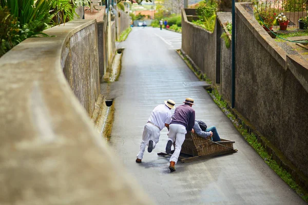 Jinetes de tabaco empujando trineo de madera cuesta abajo en Funchal, isla de Madeira, Portugal — Foto de Stock