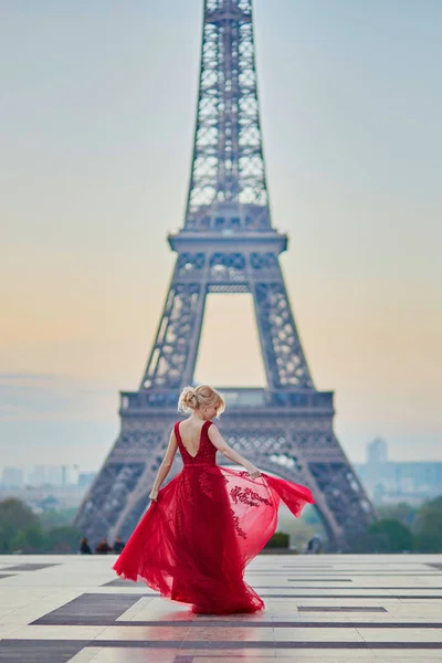 Женщина в длинном красном платье танцует возле Эйфелевой башни в Париже, Франция — стоковое фото