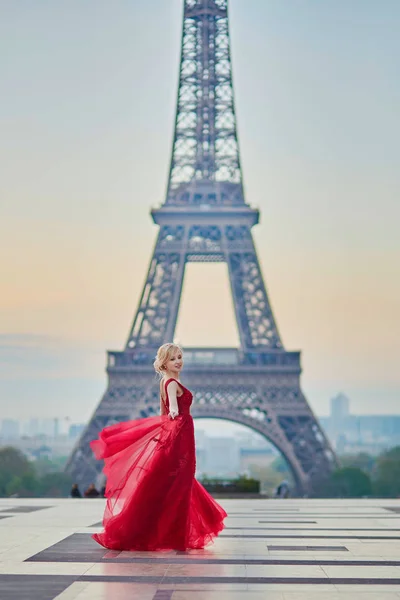 Donna in abito rosso lungo che balla vicino alla Torre Eiffel a Parigi, Francia — Foto Stock