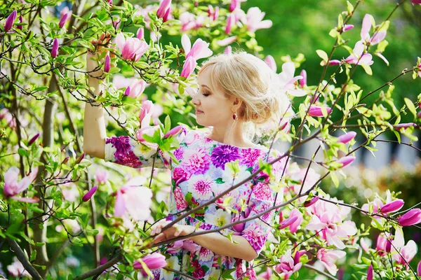 Mujer joven bajo el árbol de magnolia floreciente en un día de primavera —  Fotos de Stock