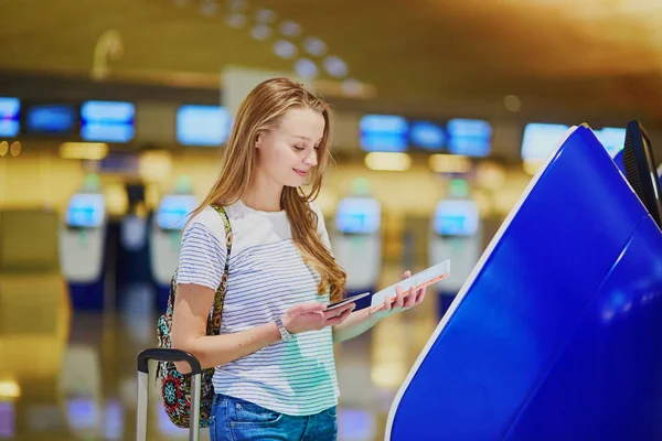 Touristenmädchen mit Rucksack und Handgepäck im internationalen Flughafen, beim Self-Check-in — Stockfoto