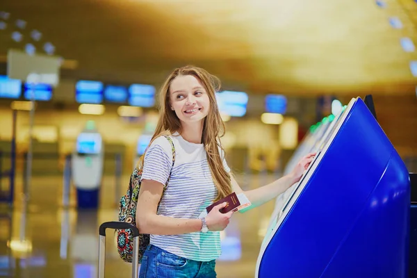 Menina turística com mochila e bagagem de mão no aeroporto internacional, fazendo check-in automático — Fotografia de Stock