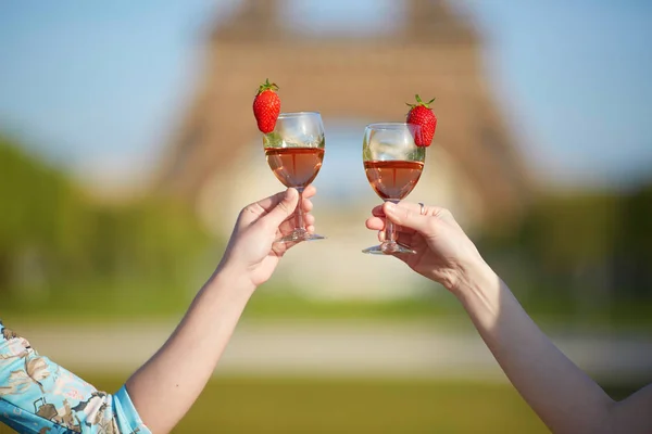 Manos de mujer sosteniendo copas de vino con torre Eiffel en el fondo —  Fotos de Stock