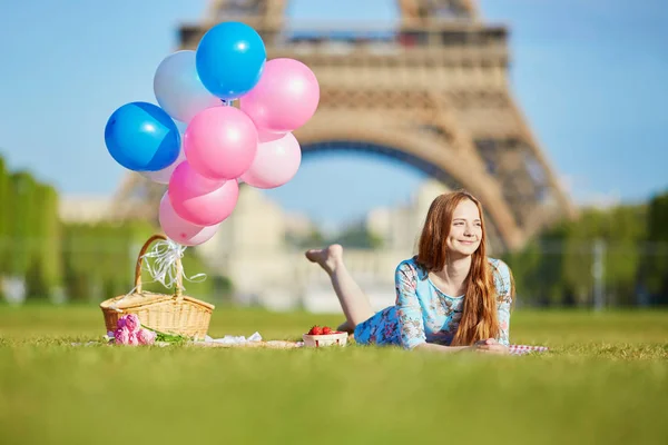 Donna in abito rosa con mazzo di palloncini che fanno un picnic vicino alla torre Eiffel a Parigi — Foto Stock