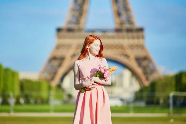 Niña con pan francés tradicional (baguette) y flores en frente de la torre Eiffel — Foto de Stock