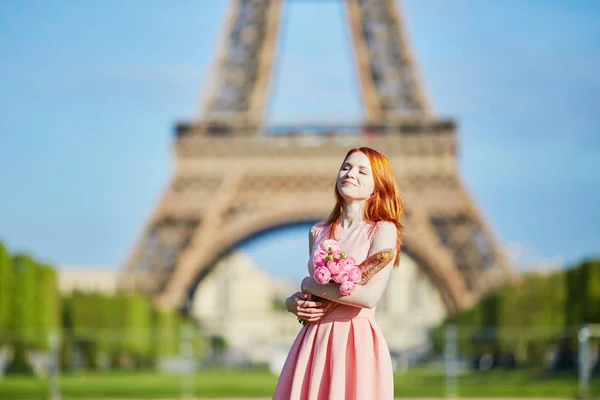 Niña con pan francés tradicional (baguette) y flores en frente de la torre Eiffel — Foto de Stock