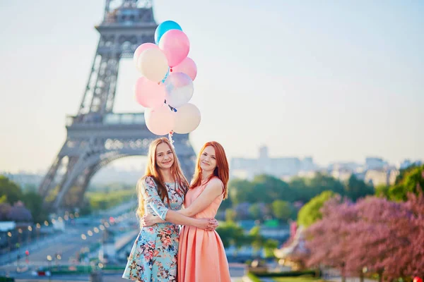 Two girls with bunch of balloons in front of the Eiffel tower — Stock Photo, Image