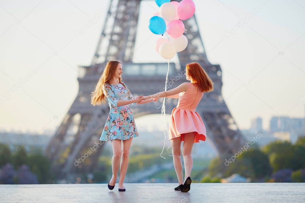Two girls with bunch of balloons in front of the Eiffel tower