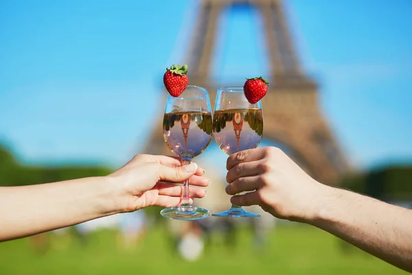 Casal segurando copos com vinho na frente da torre Eiffel — Fotografia de Stock