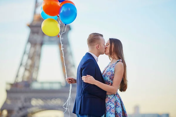 Pareja con globos de colores besándose cerca de la torre Eiffel —  Fotos de Stock