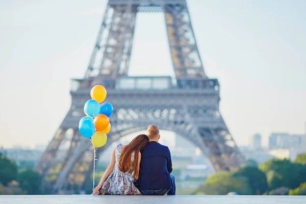 Pár s barevnými balónky při pohledu na Eiffelovu věž — Stock fotografie