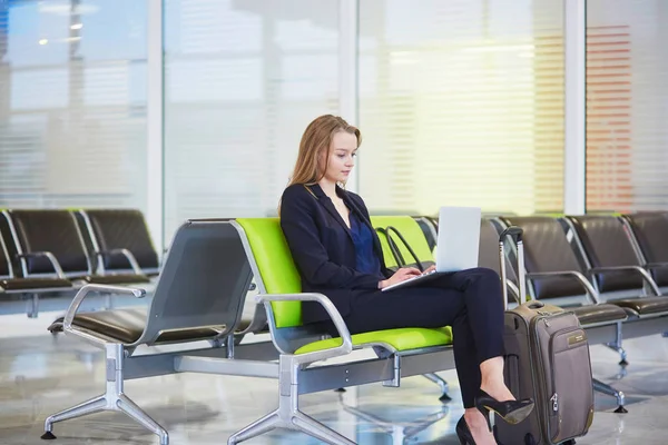 Vrouw in de internationale luchthaven, die op haar laptop werkt — Stockfoto