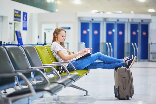 Young travelerin international airport reading a book while waiting for her flight — Stock Photo, Image