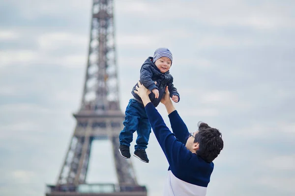 Padre arrojando a su hijito al aire cerca de la torre Eiffel —  Fotos de Stock