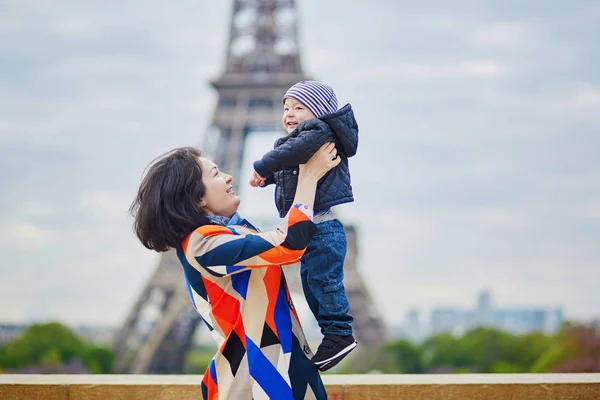 Madre lanzando a su pequeño hijo en el aire cerca de la torre Eiffel —  Fotos de Stock