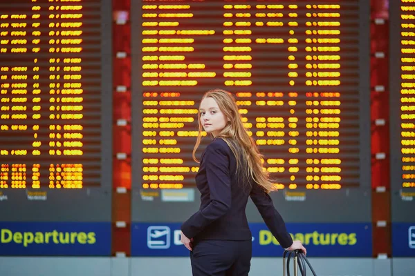 Mulher com bagagem de mão no terminal do aeroporto internacional, olhando para a placa de informações — Fotografia de Stock