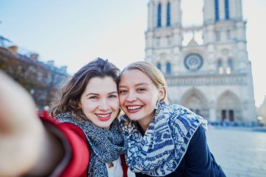 İki genç kız selfie alarak Notre-Dame de Paris yakınındaki